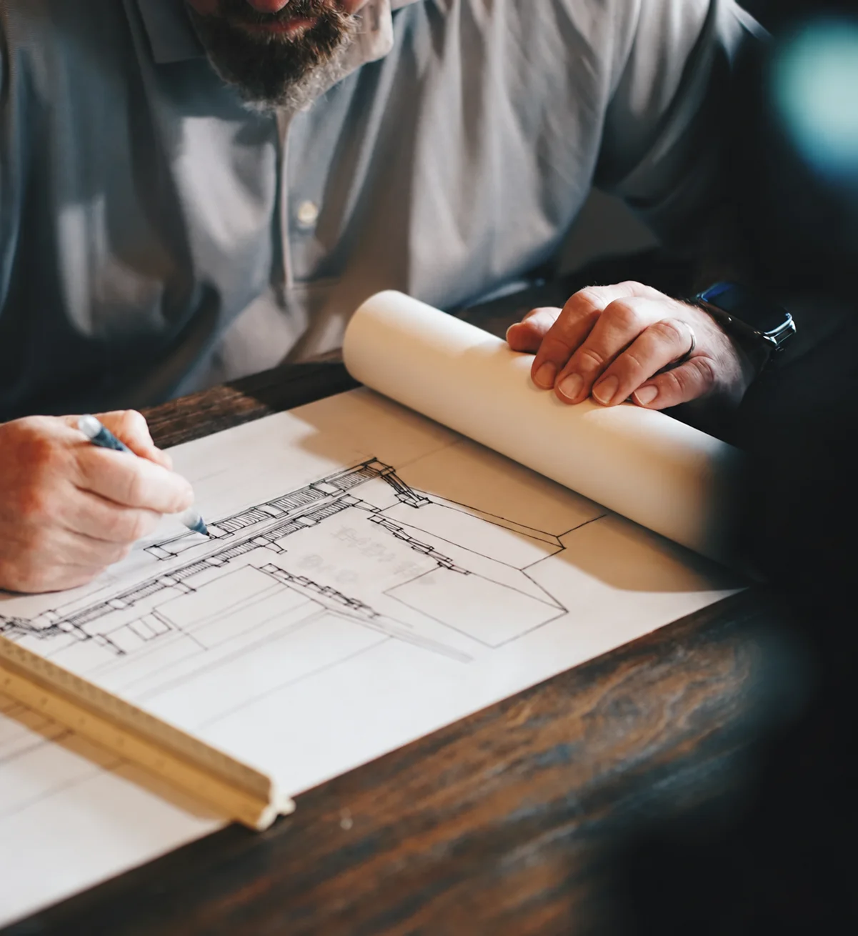 Un professionnel travaille à la main sur un plan technique, photographie d’illustration
